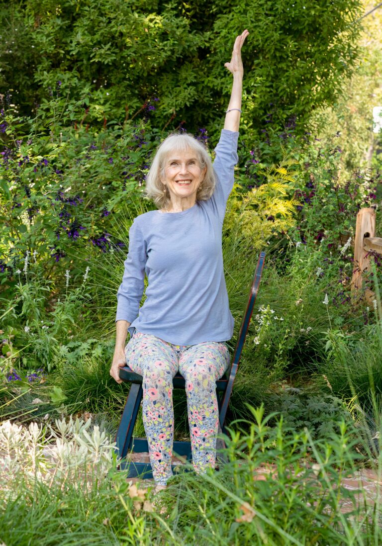 Chair yoga with 1 arm up in front garden