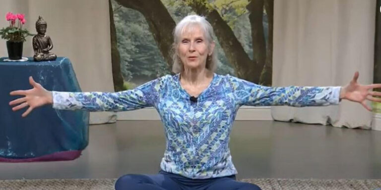 Patricia Becker yoga teacher seated on mat with open arms b