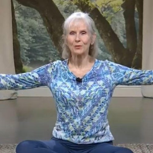 Patricia Becker yoga teacher seated on mat with open arms b